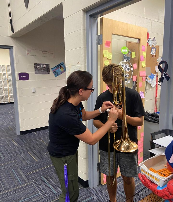 Mrs. Cordell helping Sophomore trombone player Zachery Smith fix his instrument.